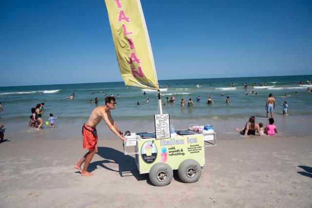 A worker pushes an Italian Ice cart on the beach during a heatwave in Carolina Beach, North Carolina, on July 3, 2026. Blistering temperatures and humidity has gripped swaths of the United States this week, with more to come for the densely populated East Coast as the nation co-hosts the World Cup and prepares to celebrate its 250th birthday on July 4. The heat wave that has been broiling the Midwest is intensifying in the Northeast, with temperatures surpassing 100F (38C) in cities including New York, Philadelphia and Washington. (Photo by Allison Joyce / AFP)