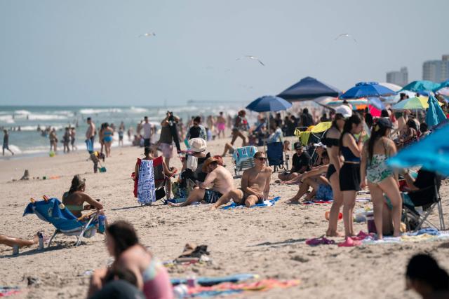 People are seen on the beach during a heatwave in Carolina Beach, North Carolina, on July 3, 2026. Blistering temperatures and humidity has gripped swaths of the United States this week, with more to come for the densely populated East Coast as the nation co-hosts the World Cup and prepares to celebrate its 250th birthday on July 4. The heat wave that has been broiling the Midwest is intensifying in the Northeast, with temperatures surpassing 100F (38C) in cities including New York, Philadelphia and Washington. (Photo by Allison Joyce / AFP)