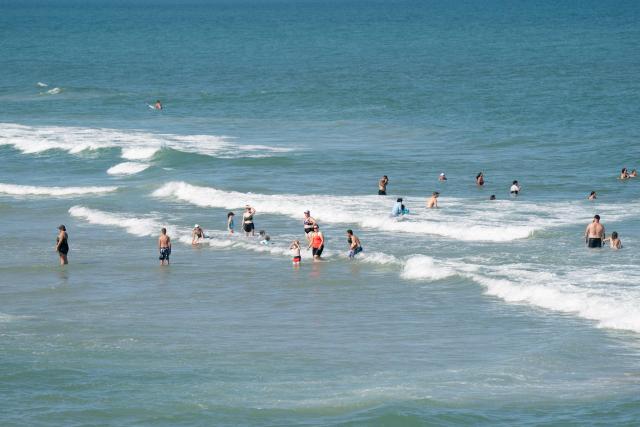 People cool off in the ocean during a heatwave in Carolina Beach, North Carolina, on July 3, 2026. Blistering temperatures and humidity has gripped swaths of the United States this week, with more to come for the densely populated East Coast as the nation co-hosts the World Cup and prepares to celebrate its 250th birthday on July 4. The heat wave that has been broiling the Midwest is intensifying in the Northeast, with temperatures surpassing 100F (38C) in cities including New York, Philadelphia and Washington. (Photo by Allison Joyce / AFP)