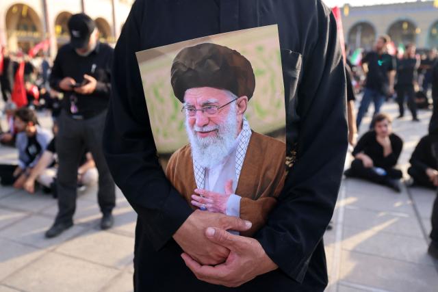 A mourner holds a portrait of Iran's slain supreme leader Ayatollah Ali Khamenei at the start of his funeral ceremonies at the Grand Mosalla in Tehran on July 4, 2026. Funeral ceremonies for Iran's supreme leader Ali Khamenei officially began on July 4, state television reported, an event drawing thousands and intended to serve as a show of strength to the Islamic republic's foes. (Photo by Atta KENARE / AFP) / 