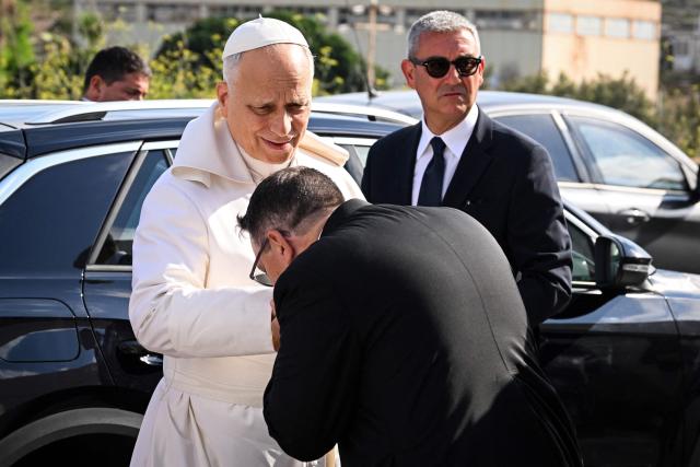 Pope Leo XIV (rear C) is welcomed by Parish of Lampedusa Carmelo Rizzo (front C) upon his arrival for a one day visit to Lampedusa island, south of Sicily, on July 4, 2026. (Photo by Tiziana FABI / POOL / AFP)