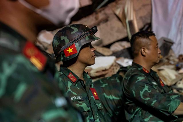 Vietnamese rescuers look on as they work among the ruins of the Oasis Beach residential building for a rescue operation during which they pulled out alive from the rubbles the police chief of La Guaira, Vice Admiral Gustavo Matamoros, in Playa Grande, La Guaira state, on July 3, 2026. The death toll from Venezuela's devastating twin earthquakes has risen to 2,645, with more than 12,600 injured and thousands mores reported still missing, according to new official figures. (Photo by Miguel MEDINA / AFP)