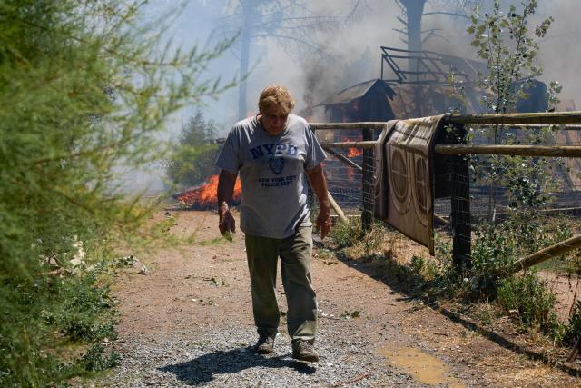 A resident walks past a structure engulfed in flames during a fire near La Bisbal de l’Emporda, northeastern Spain on July 3, 2026. (Photo by AFP)
