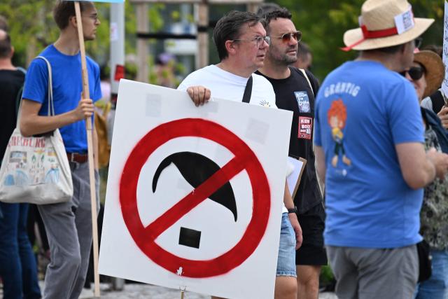A protester holds a sign showing a crossed out abstraction of German dictator Adolf Hitler during a demonstration in Erfurt, eastern Germany on July 4, 2026, where the party congress of far-right Alternative for Germany (AfD) is held. Thousands of demonstrators flooded a German city on July 4, 2026 blocking major roads and disrupting public transport, in a bid to shut down the annual congress of the far-right AfD party. (Photo by RALF HIRSCHBERGER / AFP)