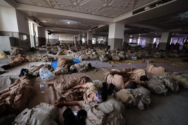 Soldiers take rest during the ongoing preparations of the funeral ceremonies for Iran's slain supreme leader Ayatollah Ali Khamenei at the Grand Mosalla in Tehran on July 4, 2026. Vast crowds of Iranians loyal to the Islamic republic massed in Tehran on July 4 to begin almost a week of funeral ceremonies for slain supreme leader Ali Khamenei, which authorities want to send a message of defiance to the West after the war with the United States and Israel. (Photo by ATTA KENARE / AFP) / 