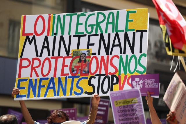 A protester holds a placard reading "Comprehensive law now. Protect our children" during a demonstration against sexual violence against women and children, called by the Women's Foundation, at Place de la Bastille central Paris, on July 4, 2026. (Photo by ROMAIN PERROCHEAU / AFP)