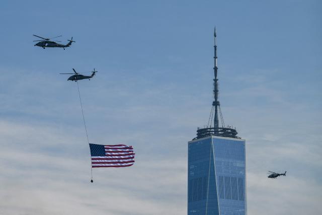 Helicopters fly the American flag past One World Trade Center, Freedom Tower ahead of the Sail4th 250 parade of ships in New York Harbor for the United States 250th anniversary on Independence Day in New York on July 4, 2026. Millions of Americans celebrate the country's 250th birthday on July 4, 2026, as the landmark celebration comes at a time of deep political division, with a president determined to put his stamp on the festivities. (Photo by ANGELA WEISS / AFP)