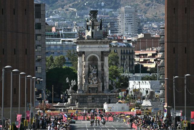 The team Caja Rural-Seguros RGA cycles next to the Venetian Towers at the Plaça d'Espanya during the 1st stage of the 113th edition of the Tour de France cycling race, a 19,6 km team time trial stage in and around Barcelona in northeastern Spain, on July 4, 2026. (Photo by Jeff PACHOUD / AFP)