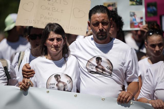 Louis's father Nicolas Herve (R) and his partner attend a tribute march to Louis, a teenager killed in an ambush in Narbonne, in Carcassonne, southwestern France, on July 4, 2026. Several hundred people took part on July 4, 2026, afternoon in Carcassonne in a silent march for Louis, a 17-year-old teenager who died at the end of June from injuries sustained in a beating, on the site of a construction project in Narbonne, on the evening of June 19, during an ambush filmed by his attackers. Left unconscious at the scene, he was hospitalized the next day after being discovered by a worker, but died from his injuries on June 23. (Photo by Valentine CHAPUIS / AFP)