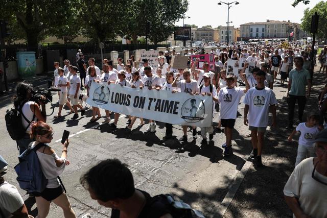 Demonstrators hold a banner reading "Louis we love you" as they attend a tribute march to Louis, a teenager killed in an ambush in Narbonne, in Carcassonne, southwestern France, on July 4, 2026. Several hundred people took part on July 4, 2026, afternoon in Carcassonne in a silent march for Louis, a 17-year-old teenager who died at the end of June from injuries sustained in a beating, on the site of a construction project in Narbonne, on the evening of June 19, during an ambush filmed by his attackers. Left unconscious at the scene, he was hospitalized the next day after being discovered by a worker, but died from his injuries on June 23. (Photo by Valentine CHAPUIS / AFP)