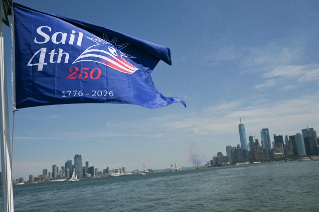 A flag on a ship sails past New York harbor during Sail 4th 250 in New York on July 4, 2026. Millions of Americans celebrated the country's 250th birthday on Saturday -- a landmark celebration that comes at a time of deep political division, with a president determined to put his stamp on the festivities. Washington's traditional fireworks display on the National Mall -- lined with monuments celebrating the nation's Founding Fathers -- has been super-sized, and is being touted as the biggest ever. (Photo by ANGELA WEISS / AFP)