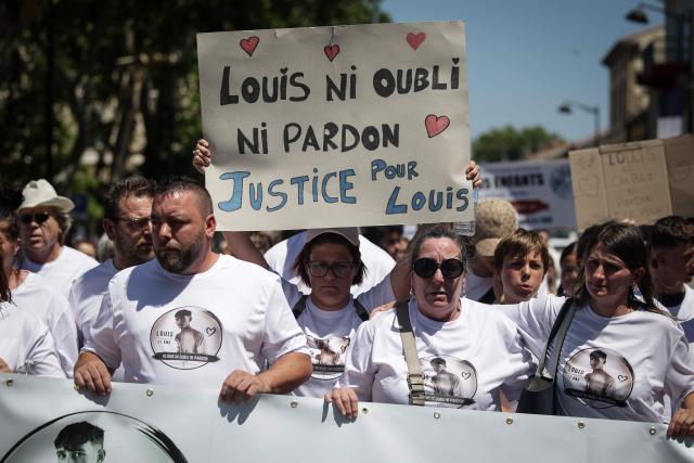 A demonstrator holds a placard reading "Louis, no forgetting no forgiving, justice for Louis" during a tribute march to Louis, a teenager killed in an ambush in Narbonne, in Carcassonne, southwestern France, on July 4, 2026. Several hundred people took part on July 4, 2026, afternoon in Carcassonne in a silent march for Louis, a 17-year-old teenager who died at the end of June from injuries sustained in a beating, on the site of a construction project in Narbonne, on the evening of June 19, during an ambush filmed by his attackers. Left unconscious at the scene, he was hospitalized the next day after being discovered by a worker, but died from his injuries on June 23. (Photo by Valentine CHAPUIS / AFP)