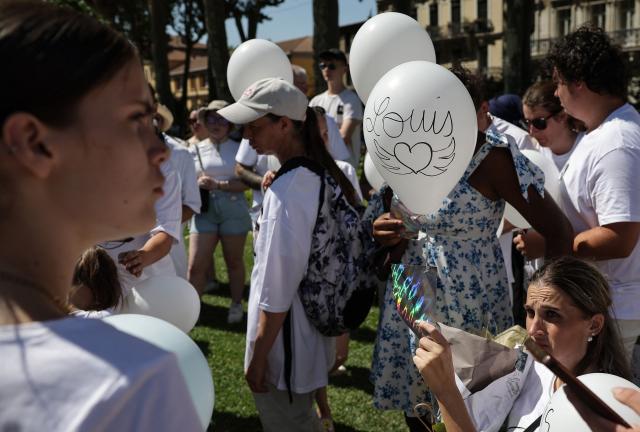 A demonstrator holds a white balloon reading "Louis" during a tribute march to Louis, a teenager killed in an ambush in Narbonne, in Carcassonne, southwestern France, on July 4, 2026. Several hundred people took part on July 4, 2026, afternoon in Carcassonne in a silent march for Louis, a 17-year-old teenager who died at the end of June from injuries sustained in a beating, on the site of a construction project in Narbonne, on the evening of June 19, during an ambush filmed by his attackers. Left unconscious at the scene, he was hospitalized the next day after being discovered by a worker, but died from his injuries on June 23. (Photo by Valentine CHAPUIS / AFP)