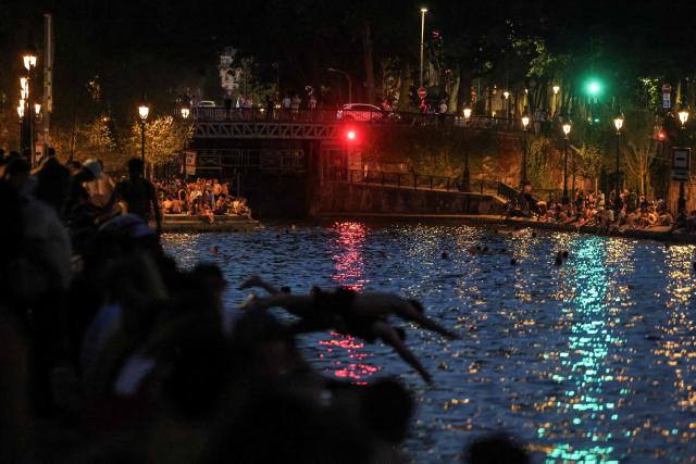 (FILES) Youths cool down in the waters of the Canal Saint-Martin as France experiences a heatwave, in Paris on June 25, 2026. The body of a man in his thirties was discovered early on the morning of July 4, 2026, in the Canal Saint-Martin, a swimming spot in eastern Paris that has been open to the public since mid-June following the severe heatwave, AFP has learnt from police sources. Firefighters and the river police recovered the body of a man, which was severely bloated – indicating he had been in the water for several days – from the Quai de Valmy at around 7.00 am on July 4, 2026. (Photo by Ludovic MARIN / AFP)