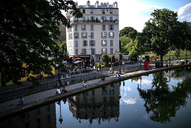 (FILES) People sit along the canal Saint-Martin in Paris on May 17, 2022 as temperatures in France this week could exceed seasonal norms by ten degrees celsius. The body of a man in his thirties was discovered early on the morning of July 4, 2026, in the Canal Saint-Martin, a swimming spot in eastern Paris that has been open to the public since mid-June following the severe heatwave, AFP has learnt from police sources. Firefighters and the river police recovered the body of a man, which was severely bloated – indicating he had been in the water for several days – from the Quai de Valmy at around 7.00 am on July 4, 2026. (Photo by Christophe ARCHAMBAULT / AFP)