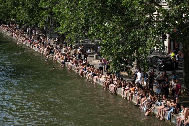 (FILES) Swimmers sunbath on the banks of the Canal Saint-Martin as France experiences a heatwave in Paris on June 20, 2026. The body of a man in his thirties was discovered early on the morning of July 4, 2026, in the Canal Saint-Martin, a swimming spot in eastern Paris that has been open to the public since mid-June following the severe heatwave, AFP has learnt from police sources. Firefighters and the river police recovered the body of a man, which was severely bloated – indicating he had been in the water for several days – from the Quai de Valmy at around 7.00 am on July 4, 2026. (Photo by ARNAUD FINISTRE / AFP)