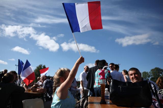 A participant holds a French flag as she attends a RN party event "La fete champetre" in Lievin, northern France on July 4, 2026. (Photo by SIMON WOHLFAHRT / AFP)