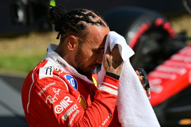 Ferrari's British driver Lewis Hamilton wipes his face after finishing with the third fastest time in the qualifying session ahead of the Formula One British Grand Prix at the Silverstone motor racing circuit in Silverstone, central England, on July 4, 2026. (Photo by Andrej ISAKOVIC / AFP)