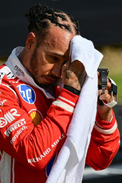 Ferrari's British driver Lewis Hamilton wipes his face after finishing with the third fastest time in the qualifying session ahead of the Formula One British Grand Prix at the Silverstone motor racing circuit in Silverstone, central England, on July 4, 2026. (Photo by Andrej ISAKOVIC / AFP)