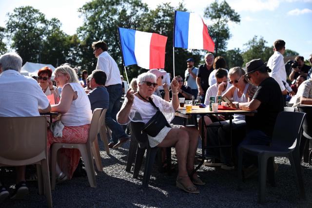 A participant holds French flags as she attends a RN party event "La fete champetre" in Lievin, northern France on July 4, 2026. (Photo by SIMON WOHLFAHRT / AFP)