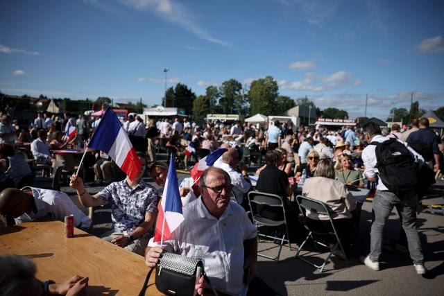 Participants hold French flags as they attend a RN party event "La fete champetre" in Lievin, northern France on July 4, 2026. (Photo by SIMON WOHLFAHRT / AFP)