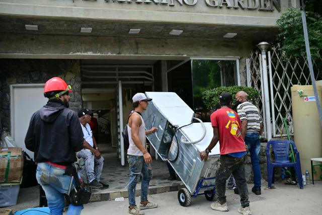 Residents take belongings out of their destroyed apartment in Catia La Mar, La Guaira State, Venezuela on July 4, 2026, following the June 24 twin earthquakes. With little hope of finding loved ones alive, frustrated families of those affected by Venezuela's double earthquakes clamor for help to recover their loved one's bodies as uncertainty grows over the death toll from the tragedy. (Photo by MARTIN BERNETTI / AFP)