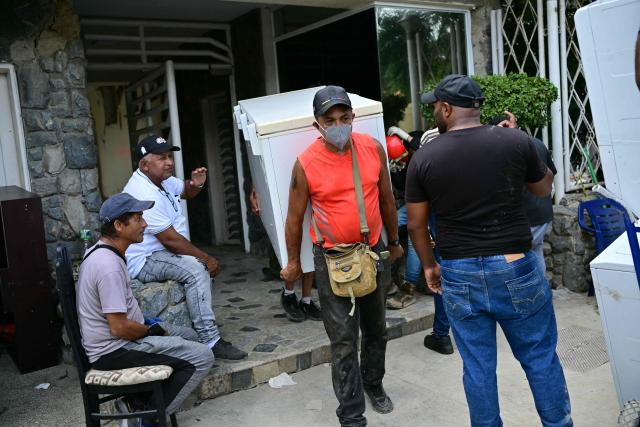 Residents take belongings out of their destroyed apartment in Catia La Mar, La Guaira State, Venezuela on July 4, 2026, following the June 24 twin earthquakes. With little hope of finding loved ones alive, frustrated families of those affected by Venezuela's double earthquakes clamor for help to recover their loved one's bodies as uncertainty grows over the death toll from the tragedy. (Photo by MARTIN BERNETTI / AFP)