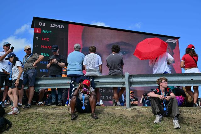Spectators look at a large video screen as they attend the qualifying session ahead of the Formula One British Grand Prix at the Silverstone motor racing circuit in Silverstone, central England, on July 4, 2026. (Photo by Andrej ISAKOVIC / AFP)