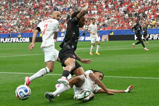 (L-R) Morocco's defender #03 Noussair Mazraoui, Canada's midfielder #17 Tajon Buchanan, and Morocco's defender #25 Redouane Halhal fight for the ball during the 2026 World Cup round of 16 football match between Canada and Morocco at the Houston Stadium in Houston on July 4, 2026.  (Photo by RONALDO SCHEMIDT / AFP)