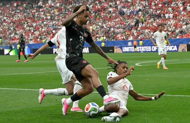 (L-R) Morocco's defender #03 Noussair Mazraoui, Canada's midfielder #17 Tajon Buchanan, and Morocco's defender #25 Redouane Halhal fight for the ball during the 2026 World Cup round of 16 football match between Canada and Morocco at the Houston Stadium in Houston on July 4, 2026.  (Photo by RONALDO SCHEMIDT / AFP)