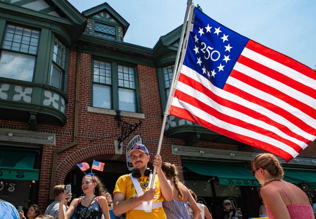 A man waves a flag during the 4th of July parade in Bristol, Rhode Island, on July 4, 2026. Millions of Americans celebrated the country's 250th birthday on Saturday -- a landmark celebration that comes at a time of deep political division, with a president determined to put his stamp on the festivities. Washington's traditional fireworks display on the National Mall -- lined with monuments celebrating the nation's Founding Fathers -- has been super-sized, and is being touted as the biggest ever. (Photo by JOSEPH PREZIOSO / AFP)