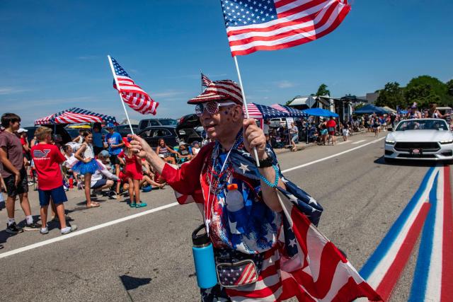 A man waves US flags as he marches during the 4th of July parade in Bristol, Rhode Island, on July 4, 2026. Millions of Americans celebrated the country's 250th birthday on Saturday -- a landmark celebration that comes at a time of deep political division, with a president determined to put his stamp on the festivities. Washington's traditional fireworks display on the National Mall -- lined with monuments celebrating the nation's Founding Fathers -- has been super-sized, and is being touted as the biggest ever. (Photo by JOSEPH PREZIOSO / AFP)