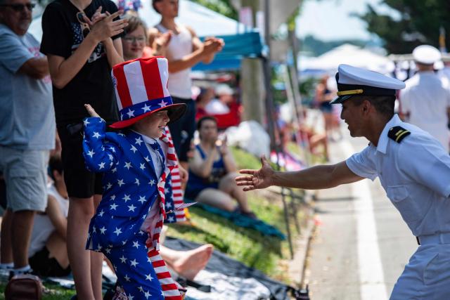 A boy dressed as Uncle Sam high fives a member of the US Navy during the 4th of July parade in Bristol, Rhode Island, on July 4, 2026. Millions of Americans celebrated the country's 250th birthday on Saturday -- a landmark celebration that comes at a time of deep political division, with a president determined to put his stamp on the festivities. Washington's traditional fireworks display on the National Mall -- lined with monuments celebrating the nation's Founding Fathers -- has been super-sized, and is being touted as the biggest ever. (Photo by JOSEPH PREZIOSO / AFP)