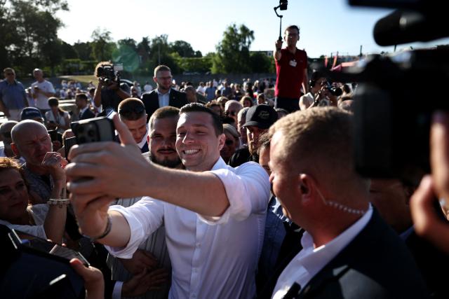 President of French far-right party Rassemblement National (RN) Jordan Bardella (C-R) takes a selfie with a supporter as he arrives to attend a RN party event "La fete champetre" in Lievin, northern France on July 4, 2026. (Photo by SIMON WOHLFAHRT / AFP)