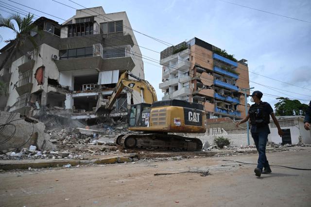 EDITORS NOTE: Graphic content / A backhoe demolishes a building in La Guaira, Venezuela on July 4, 2026, following the June 24 twin earthquakes. With little hope of finding loved ones alive, frustrated families of those affected by Venezuela's double earthquakes clamor for help to recover their loved one's bodies as uncertainty grows over the death toll from the tragedy. (Photo by Raul ARBOLEDA / AFP)