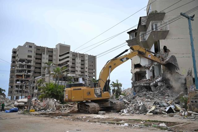 EDITORS NOTE: Graphic content / A backhoe demolishes a building in La Guaira, Venezuela on July 4, 2026, following the June 24 twin earthquakes. With little hope of finding loved ones alive, frustrated families of those affected by Venezuela's double earthquakes clamor for help to recover their loved one's bodies as uncertainty grows over the death toll from the tragedy. (Photo by Raul ARBOLEDA / AFP)