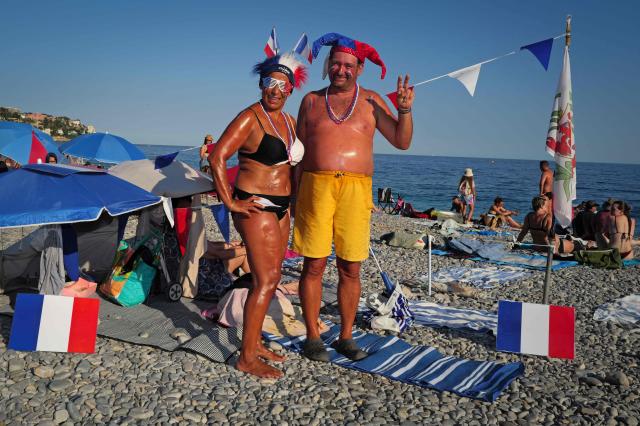 France fans Tina (L) and Thierry (R) pose on the beach ahead of the 2026 World Cup round of 16 football match between Paraguay and France in the French riviera city of Nice, on July 4, 2026. (Photo by Valery HACHE / AFP)