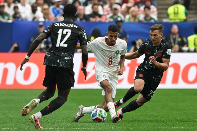 Morocco's midfielder #08 Azzedine Ounahi and Canada's defender #23 Niko Sigur fight for the ball past Canada's forward #12 Tani Oluwaseyi during the 2026 World Cup round of 16 football match between Canada and Morocco at the Houston Stadium in Houston on July 4, 2026.  (Photo by RONALDO SCHEMIDT / AFP)