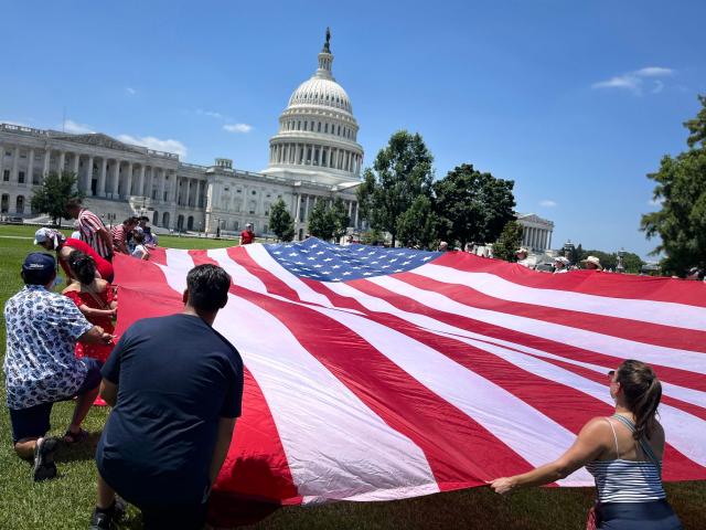 People deploy a large US flag near the US Capitol as part of the "Salute to America" Independence Day celebration on the National Mall in Washington, DC, on July 4, 2026. The nation is marking the 250th anniversary of the United States Declaration of Indpendence. (Photo by Ken Cedeno / AFP)