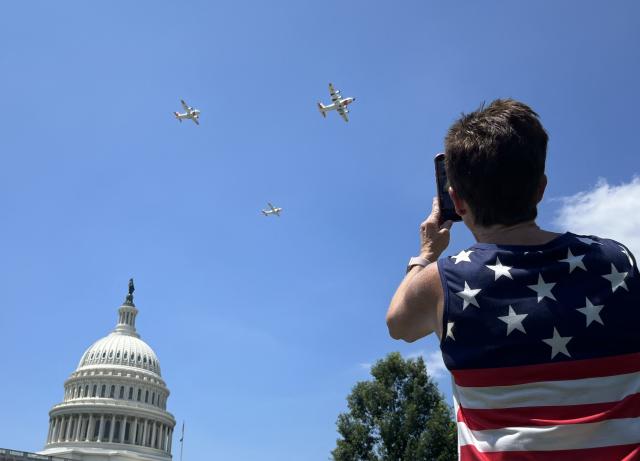 A man films US Coast Guard fixed-wing turboprop planes flying over the US Capitol as part of the "Salute to America" Independence Day celebration on the National Mall in Washington, DC, on July 4, 2026. The nation is marking the 250th anniversary of the United States Declaration of Indpendence. (Photo by Ken Cedeno / AFP)