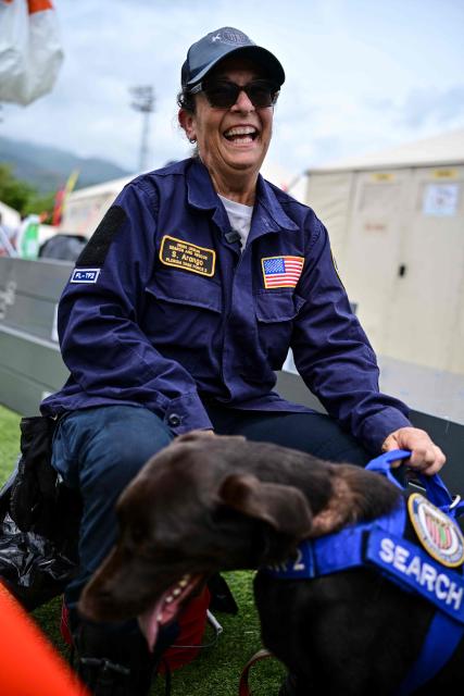 EDITORS NOTE: Graphic content / Silvya Arango of the Rescue Florida Task Force 2 team is seen with her labrador retriever dog Sisu, who participated in the rescue works, at a camp in Maiquetia, La Guaira state, Venezuela, on July 4, 2026, ten days after twin earthquakes. With little hope of finding loved ones alive, frustrated families of those affected by Venezuela's double earthquakes clamor for help to recover their loved one's bodies as uncertainty grows over the death toll from the tragedy. (Photo by MARTIN BERNETTI / AFP)