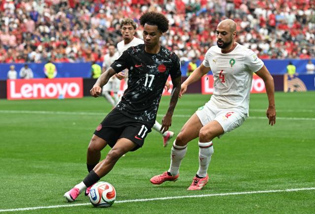 Canada's midfielder #17 Tajon Buchanan controls the ball past Morocco's midfielder #04 Sofyan Amrabat during the 2026 World Cup round of 16 football match between Canada and Morocco at the Houston Stadium in Houston on July 4, 2026.  (Photo by Paul ELLIS / AFP)