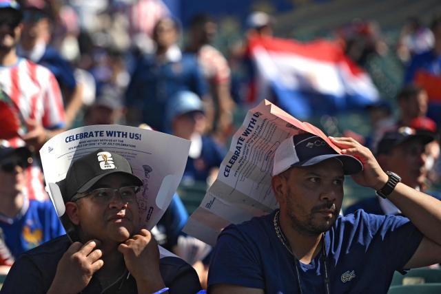 Spectators shield themselves from the heat with a leaflet ahead of the 2026 World Cup football tournament round of 16 match between Paraguay and France at Philadelphia Stadium in Philadelphia on July 4, 2026.  (Photo by MAURO PIMENTEL / AFP)