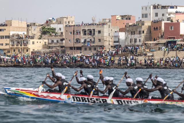 People watch as paddlers from the Xataxely community in Ngor village compete during the annual Ngor Regatta, off the coast of Ngor island, in Dakar, on July 4, 2026. Sailors and fishermen from different communities gathered for the annual Ngor Regatta, a sporting event celebrating the culture and traditions of the Lebou people, a traditional fishing community in Senegal. (Photo by PATRICK MEINHARDT / AFP)