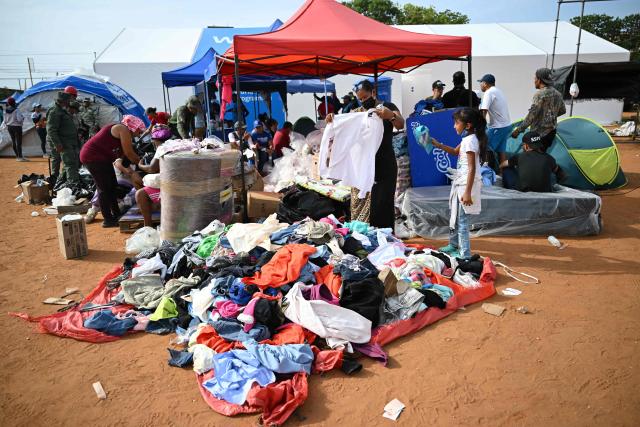 Survivors find clothes at a makeshift camp in La Guaira, Venezuela on July 4, 2026, following the June 24 twin earthquakes. With little hope of finding loved ones alive, frustrated families of those affected by Venezuela's double earthquakes clamor for help to recover their loved one's bodies as uncertainty grows over the death toll from the tragedy. (Photo by Raul ARBOLEDA / AFP)