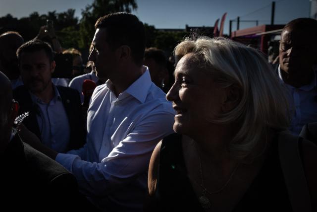 President of Rassemblement National parliamentary group Marine Le Pen (R) and French far-right party Rassemblement National (RN) president Jordan Bardella (L) shakes hands with supporters during a RN party event "La fete champetre" in Lievin, northern France on July 4, 2026. (Photo by Simon WOHLFAHRT / AFP)