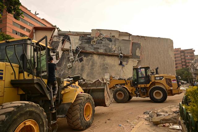 Heavy machinery is used to clear debris from a damaged building in Catia La Mar, La Guaira state, on the outskirts of Caracas, on July 4, 2026, following the June 24 twin earthquakes. The death toll from Venezuela's devastating twin earthquakes has risen to 2,954, according to official figures released on Saturday. (Photo by MARTIN BERNETTI / AFP)