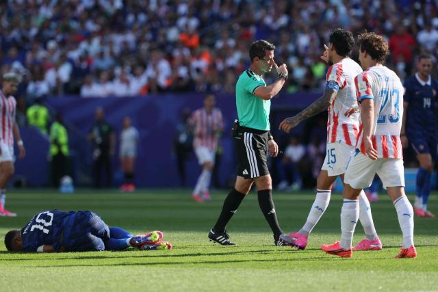 France's forward #10 Kylian Mbappe (L) reacts on the ground past Uzbek referee Ilgiz Tantashev, Paraguay's defender #15 Gustavo Gomez, and midfielder #23 Matias Galarza during the 2026 World Cup round of 16 football match between Paraguay and France at the Philadelphia Stadium in Philadelphia on July 4, 2026.  (Photo by Odd ANDERSEN / AFP)