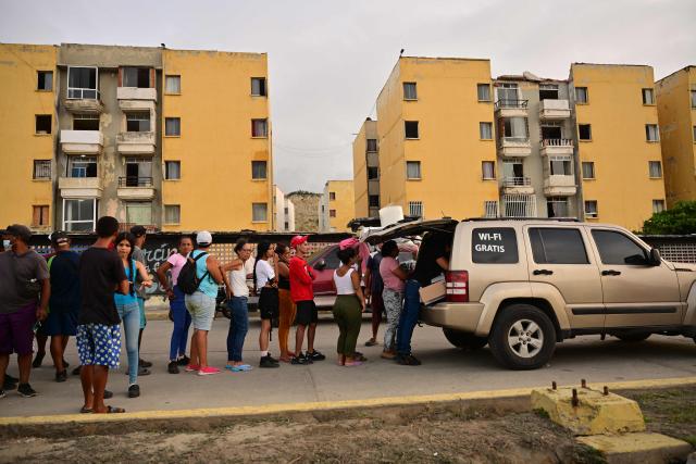 Residents affected by twin earthquakes queue to receive basic supplies distributed by volunteers in the Playa Verde sector of Catia La Mar, La Guaira state, Venezuela, on July 4, 2026. The death toll from Venezuela's devastating twin earthquakes has risen to 2,954, according to official figures released on Saturday. (Photo by MARTIN BERNETTI / AFP)