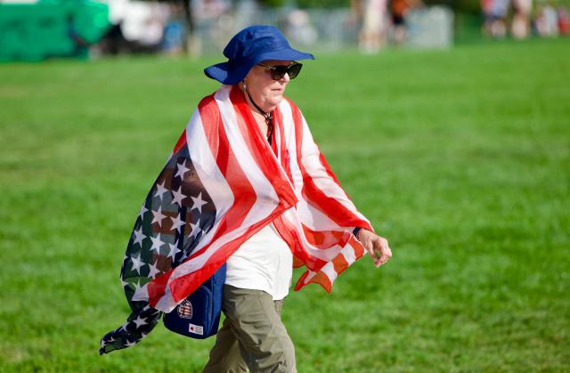 A woman is wrapped in a US flag as she attends the “Salute to America” Independence Day celebration on the National Mall in Washington, DC, on July 4, 2026. The nation is marking the 250th anniversary of the United States Declaration of Indpendence. (Photo by Amid FARAHI / AFP)